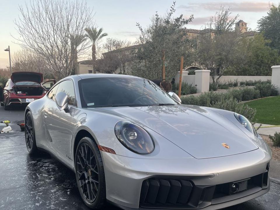 Freshly detailed silver Porsche 911 gleaming in a driveway